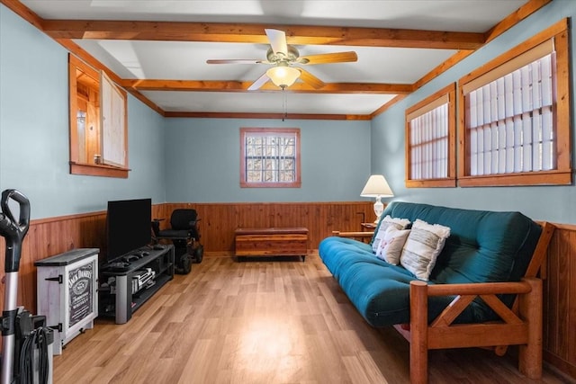 living room featuring beamed ceiling, ceiling fan, wooden walls, and light hardwood / wood-style floors