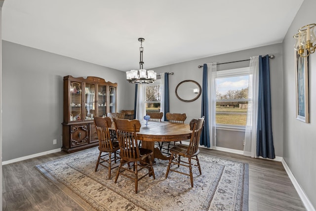 dining space with dark wood-type flooring and a notable chandelier