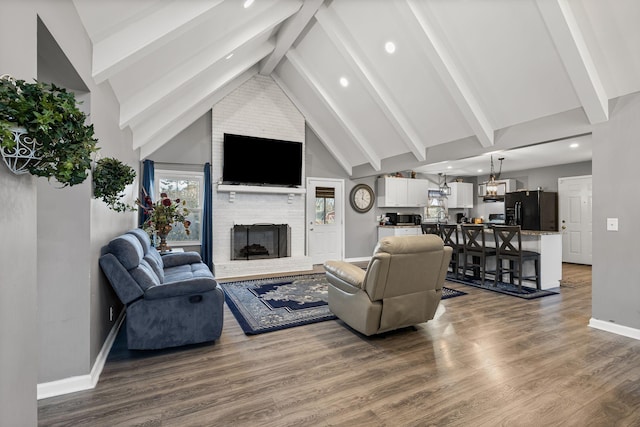 living room featuring high vaulted ceiling, a brick fireplace, beamed ceiling, and hardwood / wood-style floors