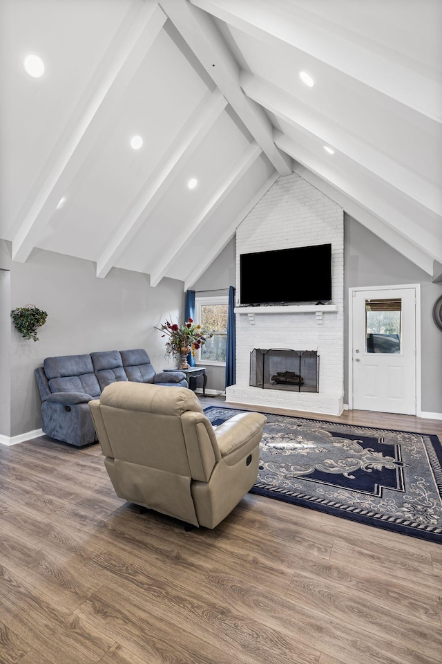 living room featuring hardwood / wood-style floors, lofted ceiling with beams, and a brick fireplace