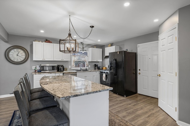 kitchen featuring white cabinetry, a kitchen island, black appliances, sink, and pendant lighting