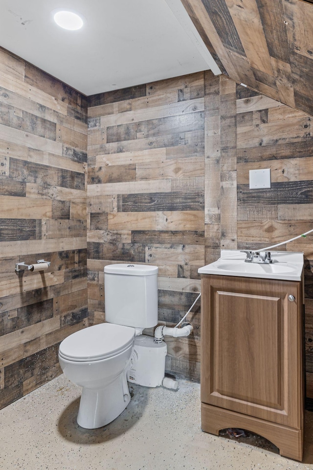 bathroom with wood walls, vanity, and toilet