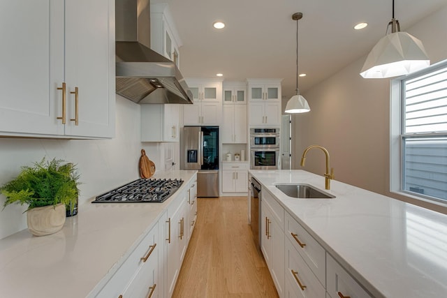 kitchen featuring white cabinetry, hanging light fixtures, light stone counters, and wall chimney exhaust hood