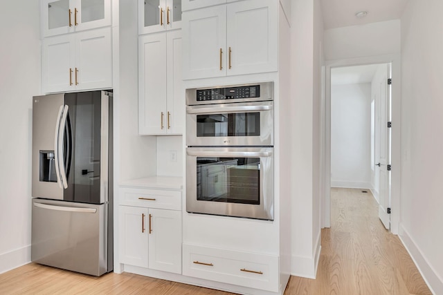 kitchen with appliances with stainless steel finishes, light hardwood / wood-style floors, and white cabinets