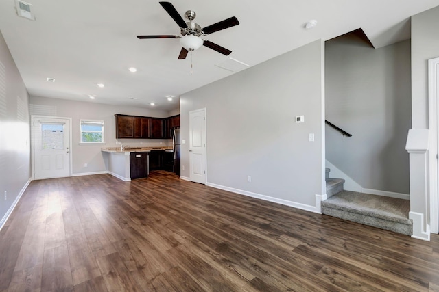 unfurnished living room featuring dark wood-type flooring and ceiling fan