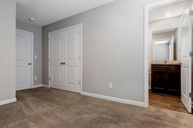 unfurnished bedroom featuring light carpet, sink, a closet, and ensuite bathroom