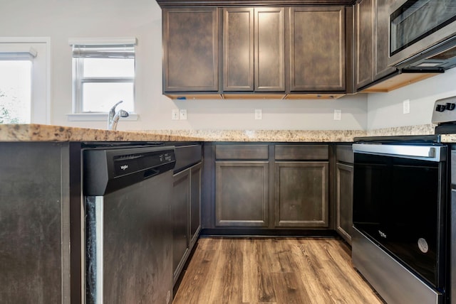 kitchen featuring dark brown cabinetry, light hardwood / wood-style flooring, light stone countertops, and appliances with stainless steel finishes