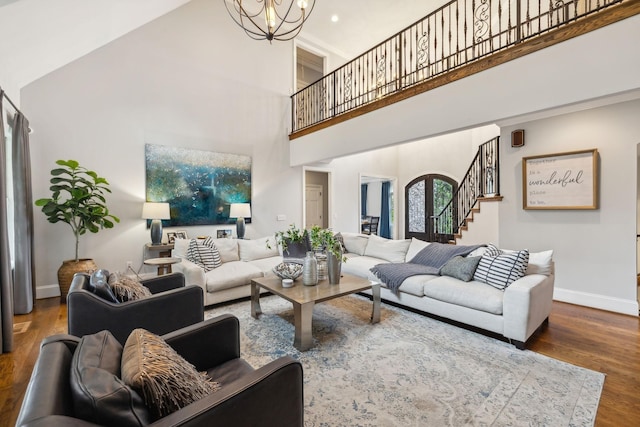 living room featuring hardwood / wood-style flooring, a towering ceiling, and an inviting chandelier