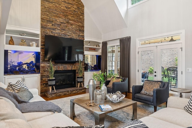 living room with a stone fireplace, french doors, a high ceiling, and light wood-type flooring