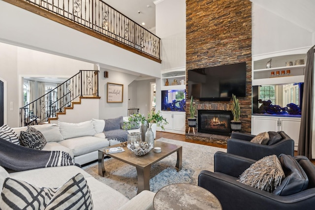 living room featuring wood-type flooring, a fireplace, and a high ceiling