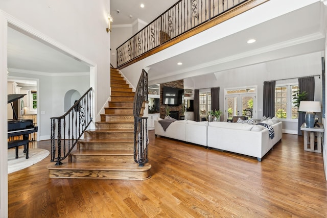 staircase featuring a towering ceiling, ornamental molding, and hardwood / wood-style floors