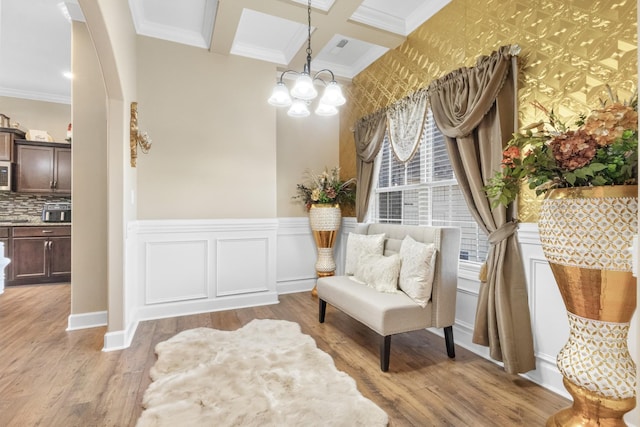 living area with coffered ceiling, a notable chandelier, crown molding, beam ceiling, and light hardwood / wood-style flooring