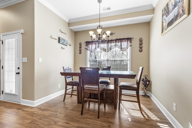 dining space featuring ornamental molding, wood-type flooring, and a notable chandelier