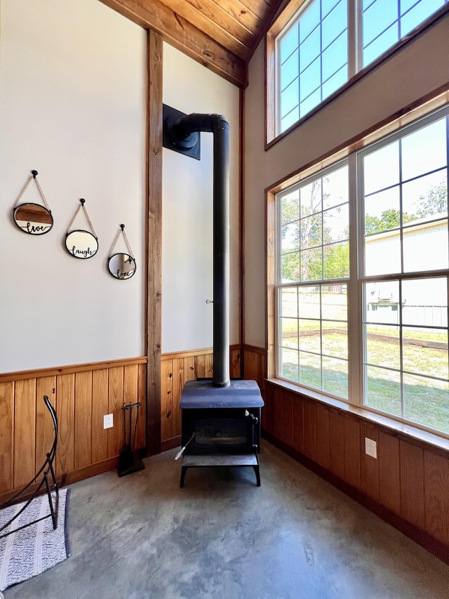 interior space featuring wood walls, concrete floors, and a wood stove