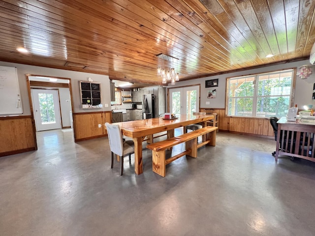 dining space featuring a wealth of natural light, concrete floors, and wood walls