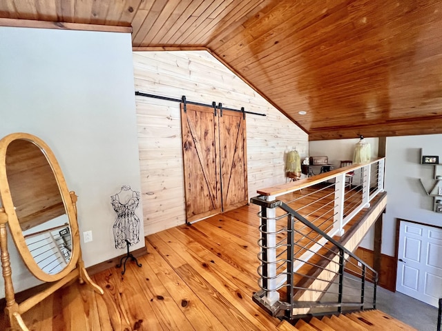 hallway with hardwood / wood-style floors, wood walls, lofted ceiling, wood ceiling, and a barn door