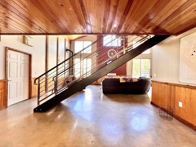 unfurnished living room featuring concrete flooring, vaulted ceiling, wooden ceiling, and wood walls