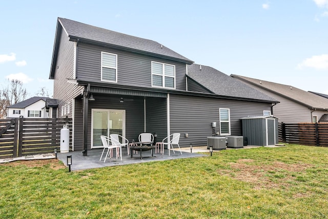 back of house with cooling unit, a storage shed, a patio area, and a lawn