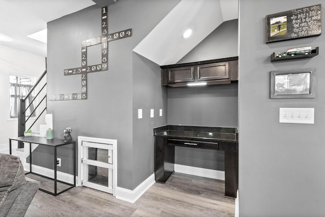 kitchen featuring dark brown cabinets, vaulted ceiling, and light wood-type flooring