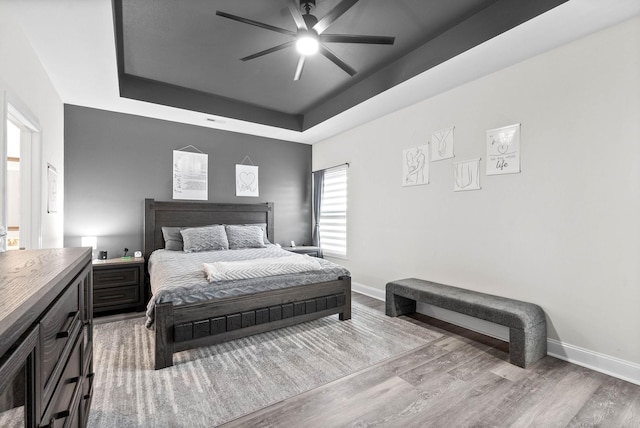 bedroom with a tray ceiling, light hardwood / wood-style flooring, and ceiling fan