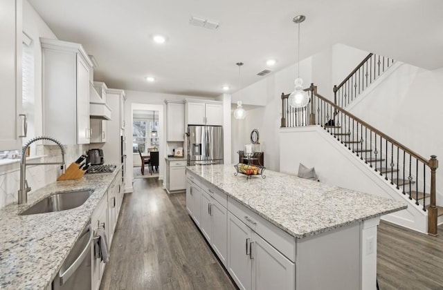 kitchen with sink, white cabinetry, decorative light fixtures, a center island, and stainless steel appliances