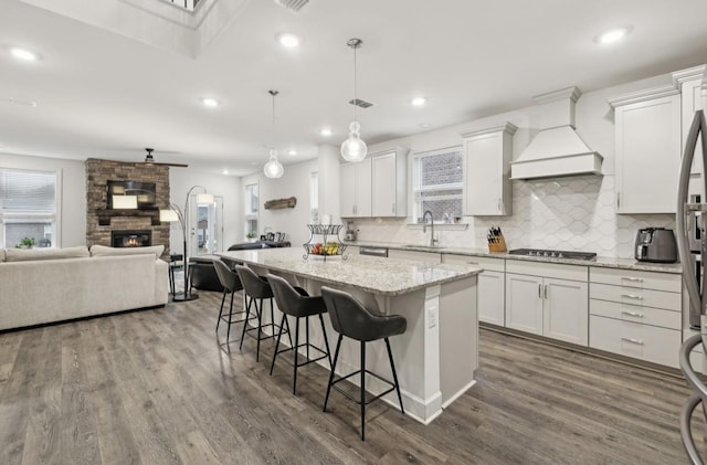 kitchen with custom range hood, hanging light fixtures, a kitchen island, and white cabinets