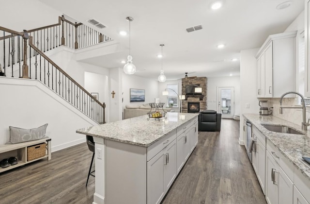 kitchen with white cabinetry, sink, hanging light fixtures, and a center island