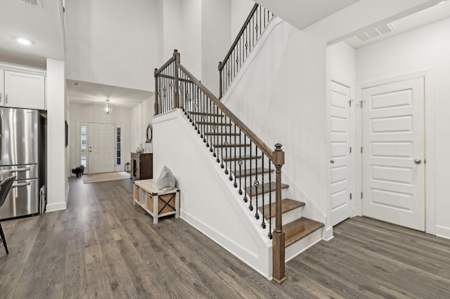 stairway featuring hardwood / wood-style flooring and a towering ceiling