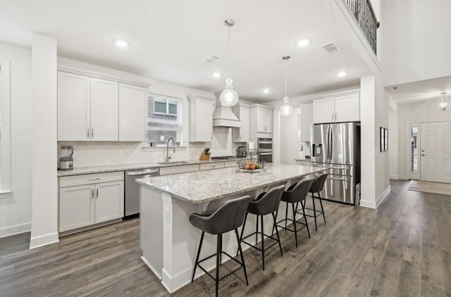 kitchen with a kitchen island, decorative light fixtures, white cabinetry, sink, and stainless steel appliances