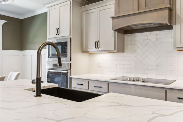 kitchen featuring crown molding, premium range hood, black electric stovetop, light stone countertops, and built in microwave