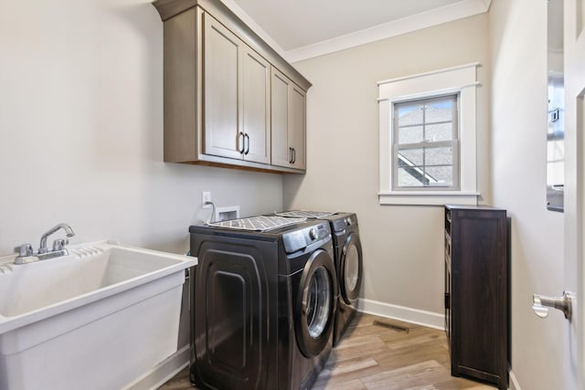 laundry area with sink, crown molding, cabinets, light wood-type flooring, and washer and clothes dryer