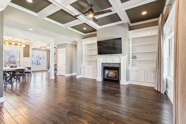 living room with dark wood-type flooring, coffered ceiling, beam ceiling, and a stone fireplace