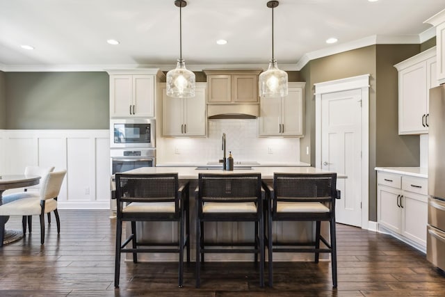 kitchen featuring dark wood-type flooring, hanging light fixtures, appliances with stainless steel finishes, an island with sink, and decorative backsplash