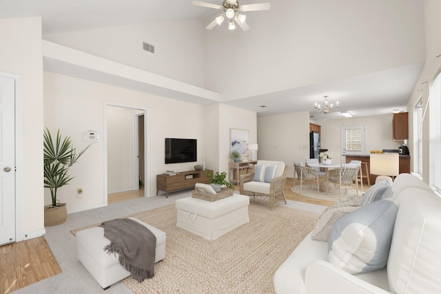 living room with ceiling fan with notable chandelier and high vaulted ceiling