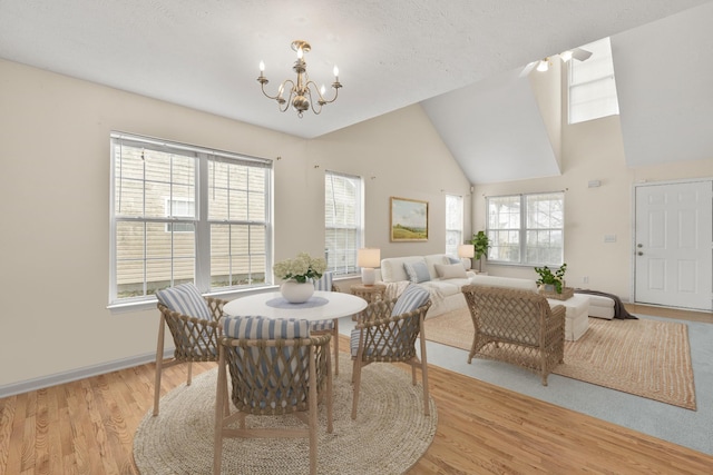 dining room with an inviting chandelier, plenty of natural light, light hardwood / wood-style floors, and vaulted ceiling