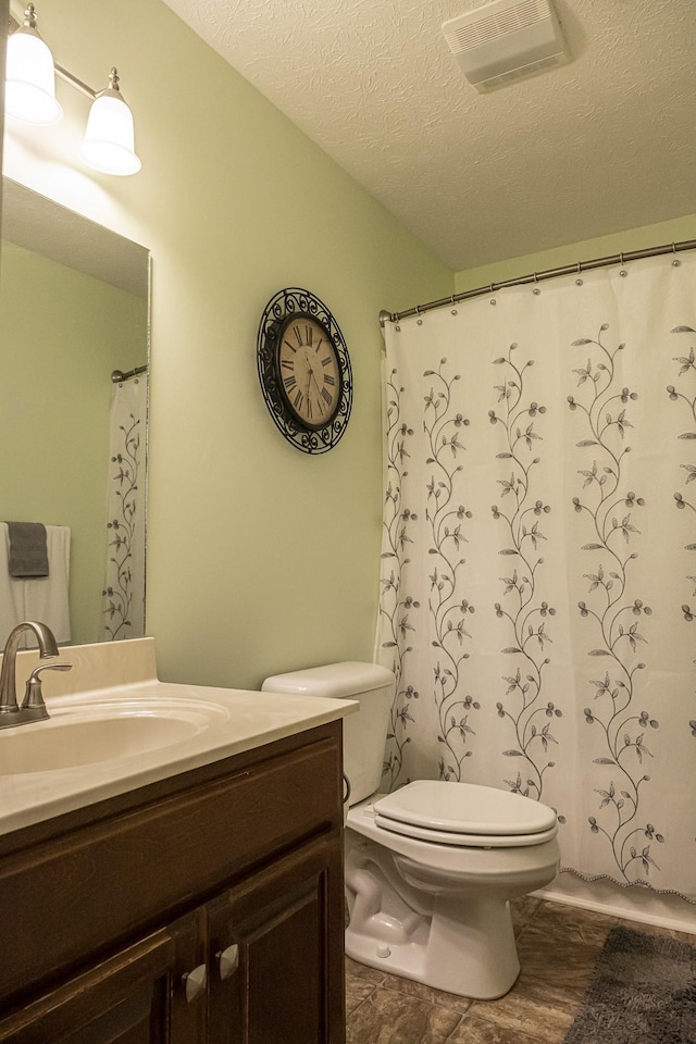 bathroom with vanity, toilet, and a textured ceiling