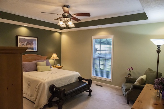 carpeted bedroom featuring ornamental molding, ceiling fan, and a tray ceiling