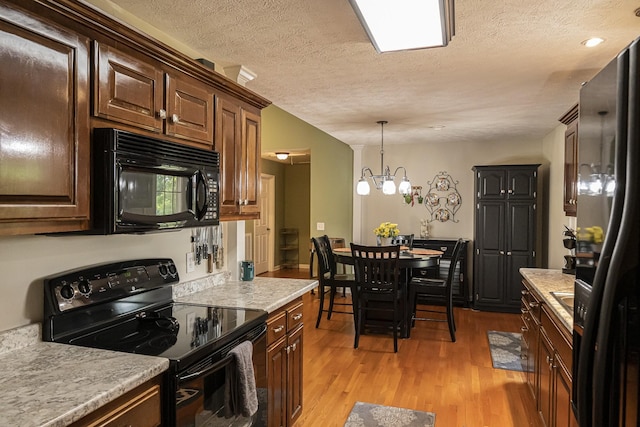 kitchen with decorative light fixtures, a chandelier, a textured ceiling, light wood-type flooring, and black appliances