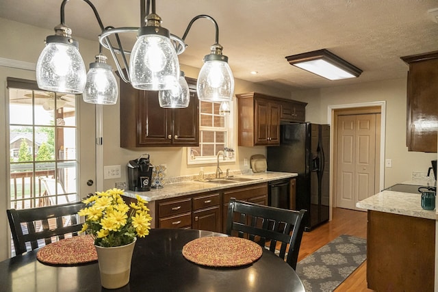 kitchen with sink, hardwood / wood-style flooring, light stone countertops, and black appliances