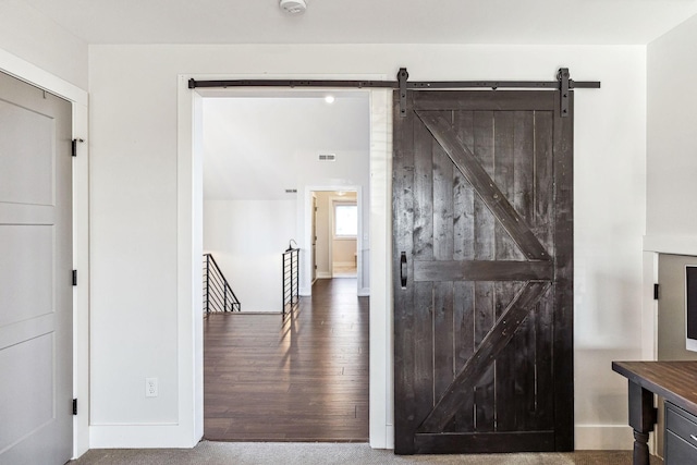 hall with wood-type flooring and a barn door