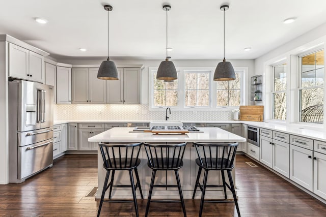 kitchen featuring decorative light fixtures, gray cabinetry, a center island, dark wood-type flooring, and high end fridge