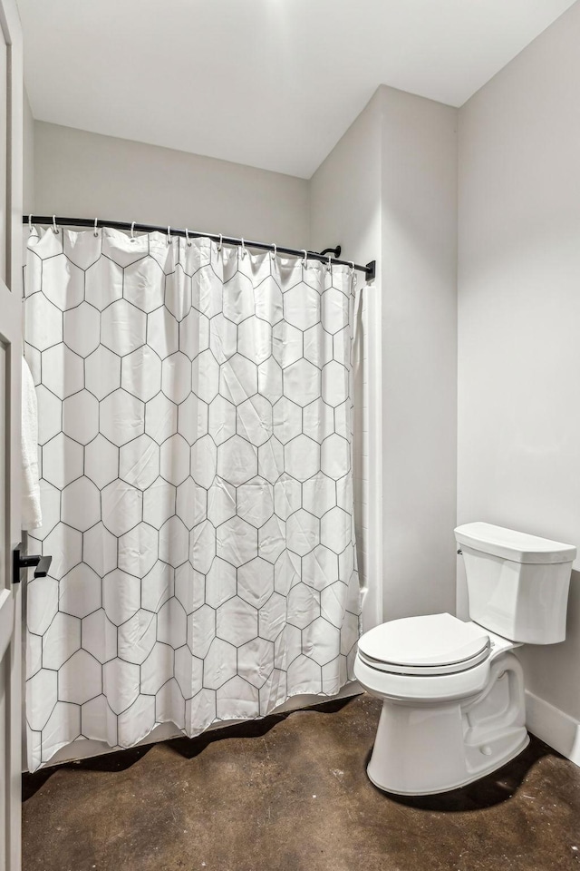 bathroom featuring concrete floors, toilet, and shower / bath combo with shower curtain