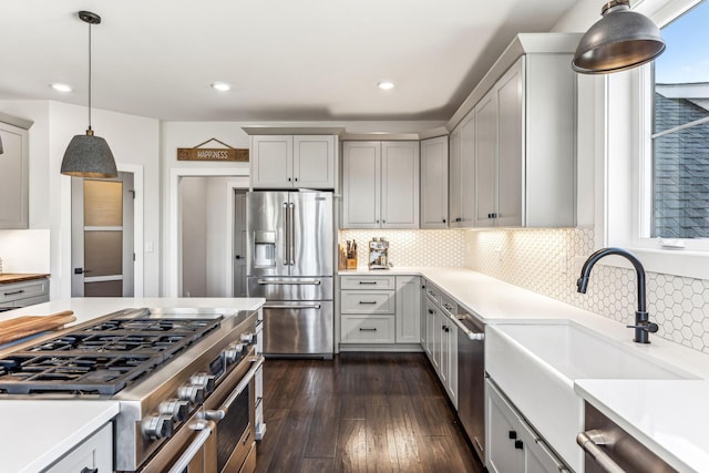 kitchen featuring pendant lighting, tasteful backsplash, sink, high end appliances, and dark wood-type flooring