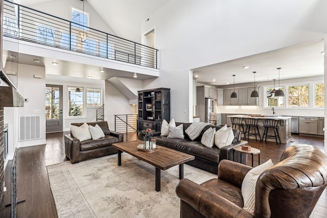 living room featuring wood-type flooring, a healthy amount of sunlight, sink, and high vaulted ceiling