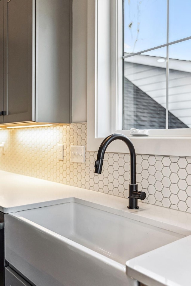 room details featuring gray cabinets, sink, and backsplash