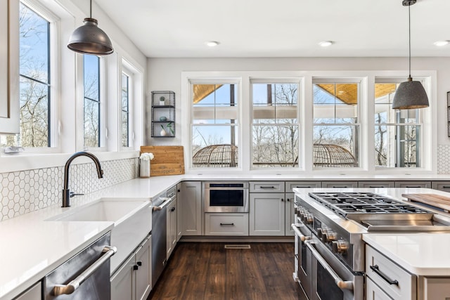 kitchen featuring sink, decorative light fixtures, dark wood-type flooring, and stainless steel appliances