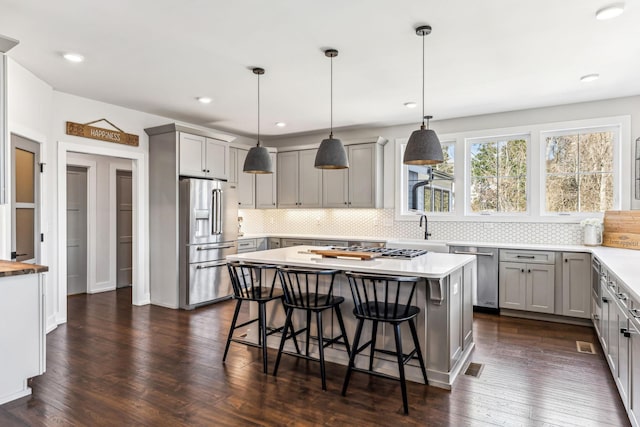 kitchen featuring stainless steel appliances, a center island, pendant lighting, and gray cabinets