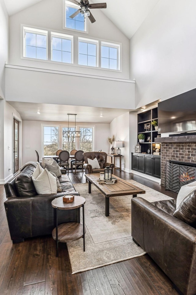 living room with built in features, dark hardwood / wood-style floors, vaulted ceiling, and a brick fireplace