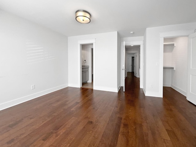 unfurnished bedroom featuring a walk in closet, dark hardwood / wood-style flooring, and a closet