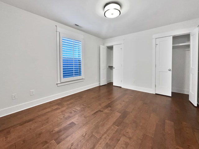 unfurnished bedroom featuring two closets and dark hardwood / wood-style flooring